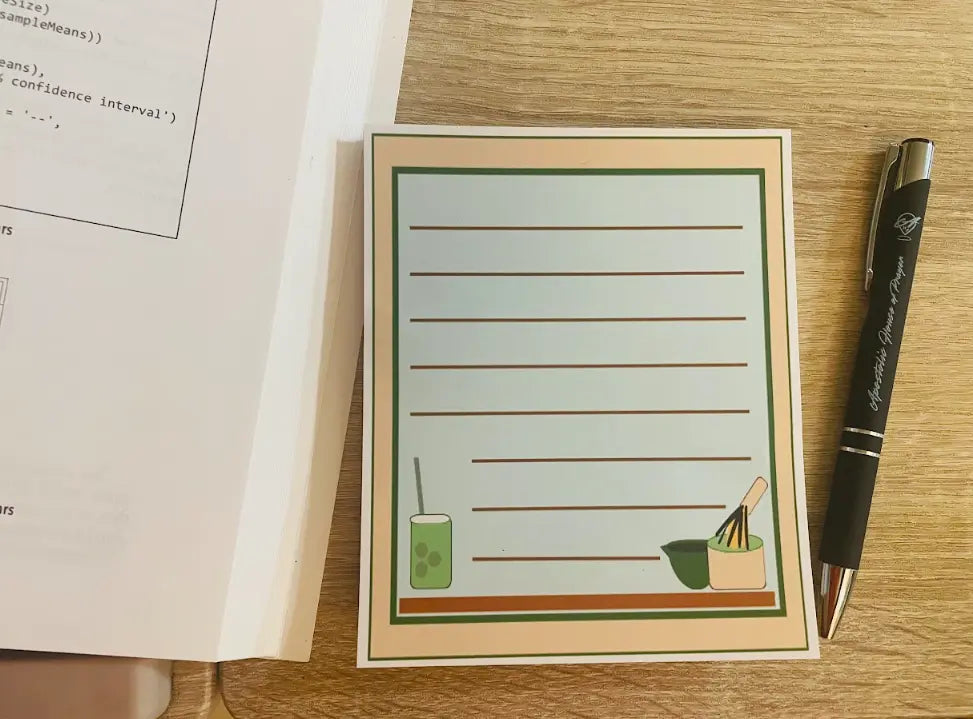 Matcha Memo Pad, 4.5 by 5.5 inch, green page with tan and dark green border, iced matcha drink with foam in bottom left, hot match and wisk in bottom right, not a sticky note pad,  Pyari Paper Shop
