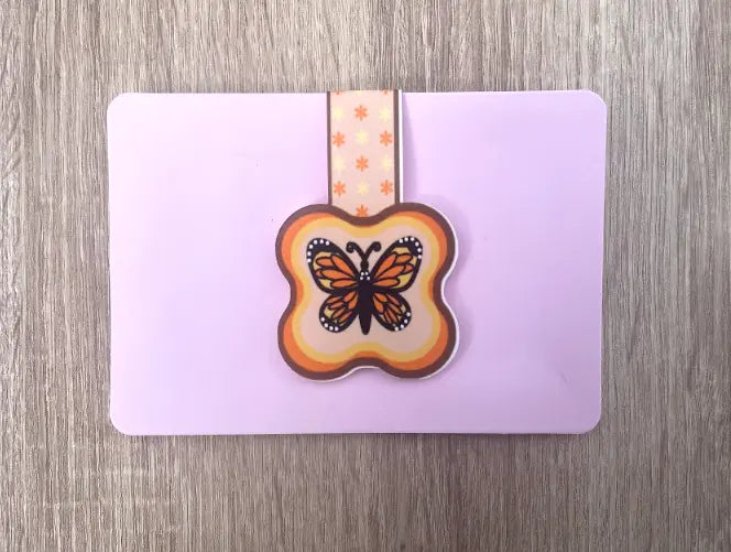 Monarch Butterfly, 2 by 3 inch Magnetic Bookmark on blush pink card packaging, Orange, yellow, black and white butterfly on light yellow background, orange and brown border, orange and yellow flowers, Pyari Paper Shop