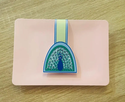 Peacock, 2 by 3 inch Magnetic Bookmark on pink card packaging, blue background, light green, light blue border, half moon shaped, peacock feathers, Pyari Paper Shop